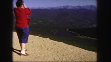 1958: women viewing mountain peaks with binoculars on windy summit COLORADO