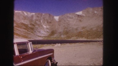 1958: view of a mountain ridge from a roadside stop while tourists take pictures