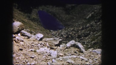 1958: a blue lake like a gem in the heart of a hill with rocks scattered