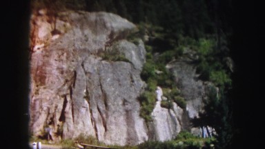 1958: rocky mountain side view with trees and blue sky