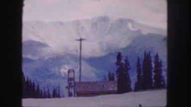 1958: amazing mountain peak behind coniferous trees under the overcast sky