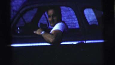 1958: young man in white t-shirt sitting inside a moving black car NEW YORK CITY