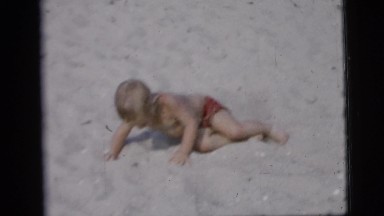 1958: woman sits on blanket at the beach while child lies on bare sand NEW YORK