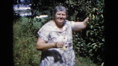 1960: old woman showing the fruit plucked from the plant in her orchard