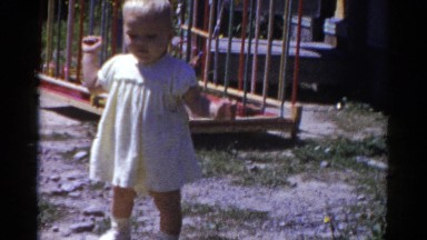 1959: a cute toddler in a yellow dress outside attempting to walk CATSKILL GAME