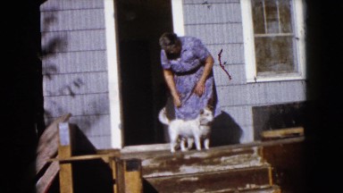1960: Dog Stands at Doorway as Woman Enters and Child Walks By