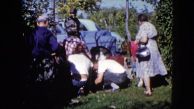 1960: various people outside doing something in the grass next to a car