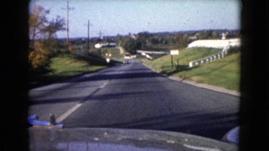 1960: rolling green hills and a white brick fence as seen from a moving car