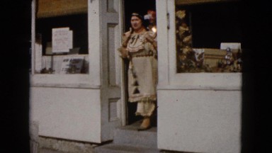 1960: two red indian women dancing in street while a third woman passes by