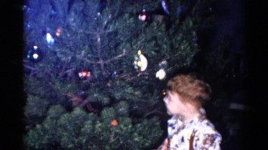 1959: a girl and two boys decorate a pine tree for christmas with ornaments