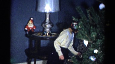 1959: a young girl and a smaller child hang ornaments on a christmas tree