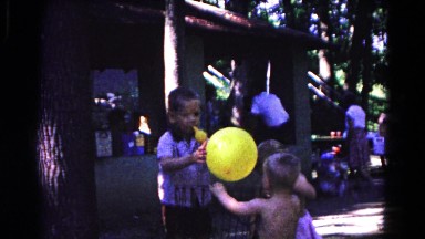1963: three little boys playing with balloons in a public area on a sunny day.