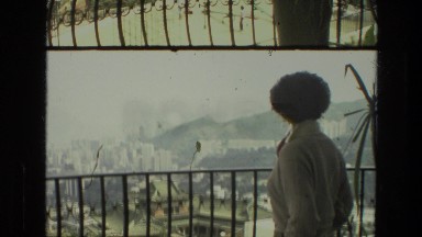 1974: person is standing on a balcony that overlooks a city on a hill