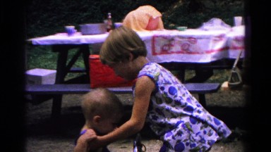 1963: little girl helping her baby brother in his seat at a park outing