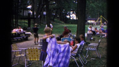 1963: adults and children gather for a picnic in a park by a playground.