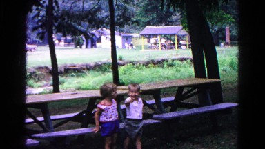 1963: two small children as they stand next to a picnic table on a park