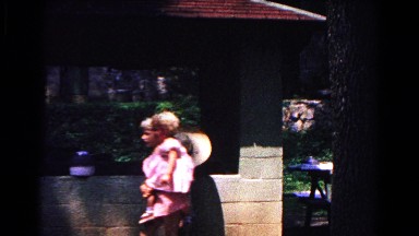 1963: a child in a large hat peering over a short cement wall COLD SPRINGS
