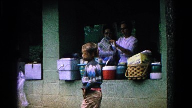 1963: women, men and children gathered outside under a covered picnic area