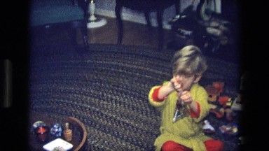 1975: little boy sitting down and opening up a present CALIFORNIA