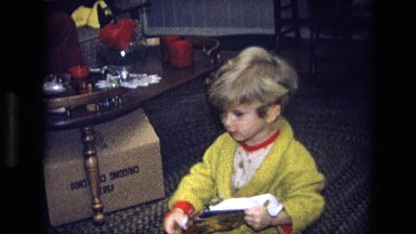 1975: a little boy opening his presents on christmas day with his family