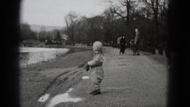 1948: cute boy winter jumpsuit walking in barren park landscape MIDDLETOWN