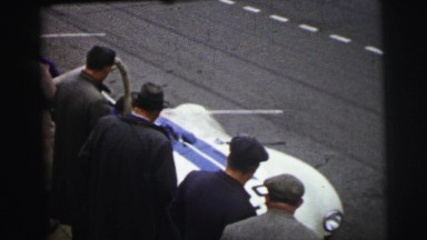 1955: white race car driving onto course while onlookers observe LE MANS
