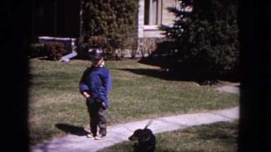 1964: Boy with Dog on Leash Standing on Sidewalk Evanston, Illinois