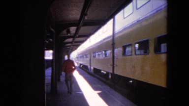 1964: man walking away on a platform as a yellow train leaves the station.