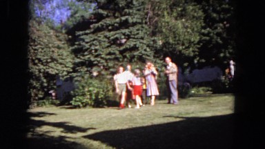 1964: adults and children assembling in front of tall pine trees and waving