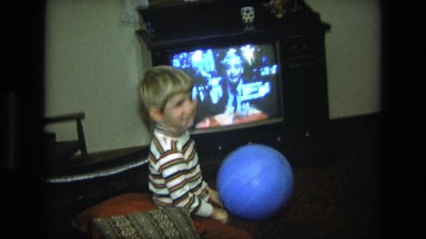 1975: a small child plays with his blue balloon in the living room