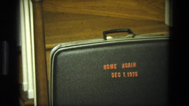 1975: a woman moving about a suitcase sitting on a step on the staircase