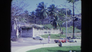 1964: Woman Walks Near Busy Street to Meet a Child Kingston, Jamaica