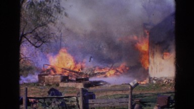 1968: house burns while man in dark blue shirt watches near a fence WAUCONDA