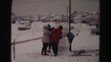 1962: Adults Building a Snowman with Hands and Shovel in Residential Hagerstown