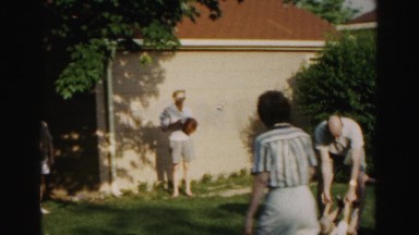 1962: man picks child up by wrists and ankles, then swings him around as people