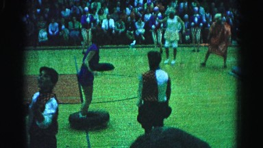 1962: people in costumes performing for a crowd on a basketball court