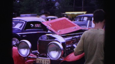 1962: a group of cars on a car show with spectators admiring the antique cars