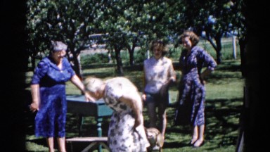 1962: four ladies, one quite elderly, pose formally in a park while dog frisks