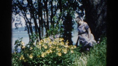 1962: a woman in a dress standing on a hillside overlooking the water