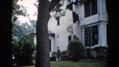 1962: an outdoor view of a beautiful two story house surrounded by trees
