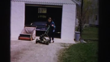 1956: a woman is seen raking with lawn mover MADISON, WISCONSIN