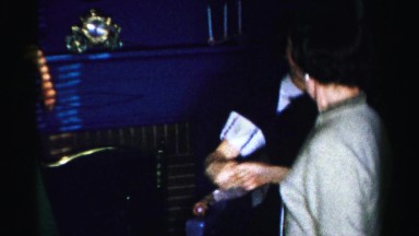 1956: a teen and an older woman both in dresses dancing in a blue living room