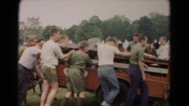1966: several men in military uniforms are pushing a truck while many more look