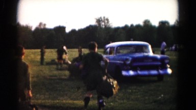 1966: several boys scouts in uniform carrying their bags to a parked car