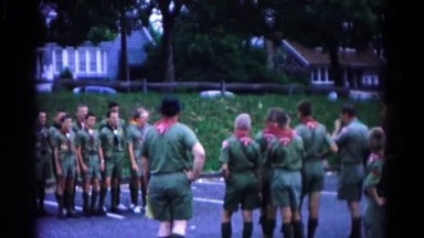1966: boy scout troop in parking lot with man taking pictures of other scouts.