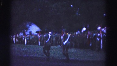 1966: two soldiers wearing shorts and white sash across chest and back walking