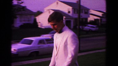1966: white suburban male in white suit and black bowtie entering car