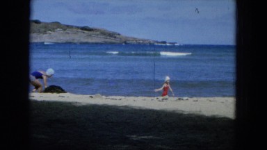 1964: two girls enjoy the sandy beach on a windy summer day. HAWAII