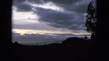 1964: Sun Trying to Shine Through Thick Clouds Over a Silhouetted Landscape