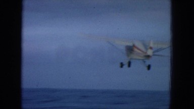 1964: a small airplane after taking off moving over some water at the coast.